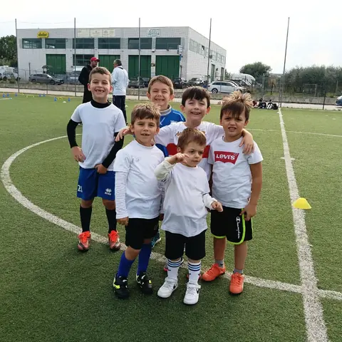 Sei bambini della scuola calcio in posa sul campo in erba sintetica