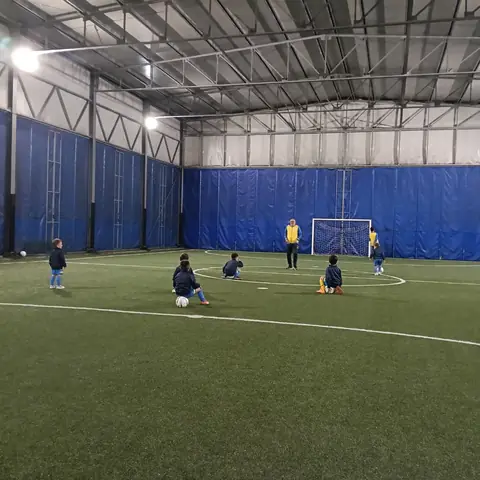Bambini che si allenano in un campo da calcio coperto
