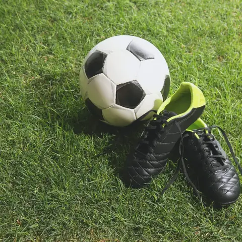 Pallone da calcio e scarpini appoggiati sull’erba